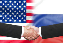 Hands shaking in front of USA and Russia flags.