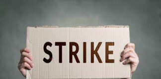 Two hands holding a cardboard sign saying STRIKE.