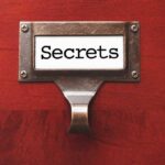 A label holder on a wooden surface with the word Secrets displayed