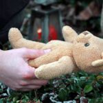 A person holding a stuffed bear in an outdoor setting