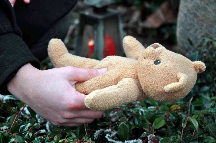 A person holding a stuffed bear in an outdoor setting