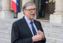 Shocking Revelation — Gates Exposes Climate Strategies’s Failures A man in formal attire speaking outdoors with a flag in the background