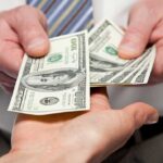 Walmart Under Pressure — Cashless Society REJECTED Two hands exchanging cash bills in a business context