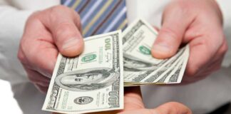 Two hands exchanging cash bills in a business context
