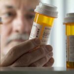 Big Pharma RECALLS 600K Bottles — Cancer Risk! An elderly man holding a prescription bottle while examining it closely