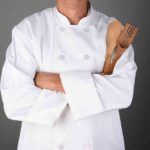 Celebrity Chef Shot Eleven Times! A chef in a white uniform holding wooden cooking utensils with crossed arms