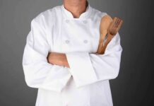 Celebrity Chef Shot Eleven Times! A chef in a white uniform holding wooden cooking utensils with crossed arms