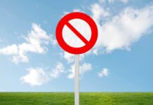 A no entry sign on a grassy field under a clear blue sky