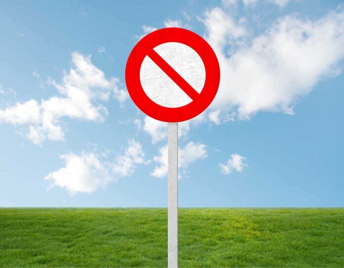 shutterstock_175115636.jpg A no entry sign on a grassy field under a clear blue sky