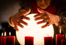 Stunning $70 Million Scam — Mother-Daughter Duo Busted A person with adorned hands hovering over a glowing crystal ball surrounded by candles