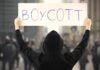 NYC Mayor’s SHOCKING Boycott Call Person holding a sign that says BOYCOTT during a protest