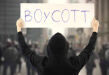 NYC Mayor’s SHOCKING Boycott Call Person holding a sign that says BOYCOTT during a protest
