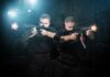 Shots Fired—Trump Agents Ambushed! Two tactical operators aiming firearms in a dimly lit urban setting
