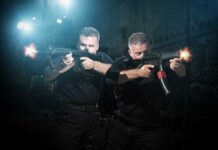 Two tactical operators aiming firearms in a dimly lit urban setting