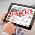 Pension Scammer Dresses as Dead Mom Person holding a tablet displaying a news website with a 'FAKE' stamp