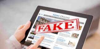 Person holding a tablet displaying a news website with a 'FAKE' stamp