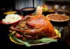 A beautifully roasted turkey on a festive table surrounded by side dishes and decorations