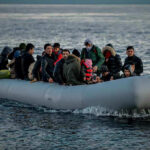People on a packed raft in open water.