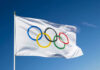 MASSIVE Doping Scandal Rocks Olympics Olympic flag waving against clear blue sky.
