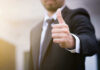 Person in suit giving thumbs up gesture.