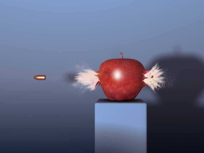 A red apple being struck by a bullet, showing an explosion effect