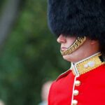 British soldier in ceremonial uniform with a black fur hat standing guard