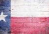 Abbott’s Shocking Move — UNPRECEDENTED Branding! Texas flag displayed on a wooden background