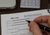 Hand filling out an SBA loan application form on a desk