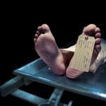 Feet of a deceased person on a coroners table with an identification tag