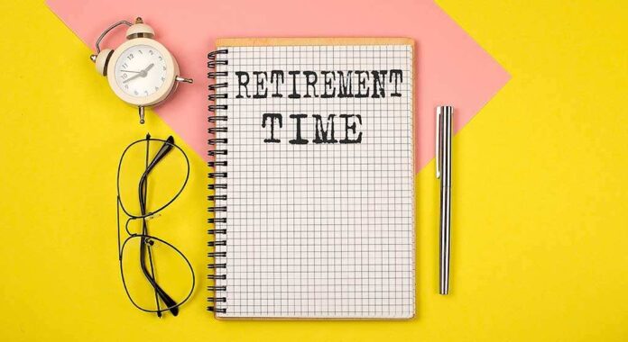 shutterstock_1936795690 (1).jpg Notebook with RETIREMENT TIME written on it, accompanied by glasses and an alarm clock