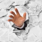 BURIED ALIVE — Girl’s Miracle Horror Story A hand reaching out from a pile of crumpled papers, symbolizing being overwhelmed by paperwork