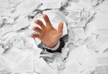 A hand reaching out from a pile of crumpled papers, symbolizing being overwhelmed by paperwork