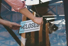 Hand placing closed sign on glass door