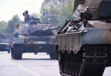 Tanks on a road with soldiers inside.