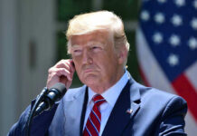 DAVOS BOMBSHELL: Trump’s 59-Nation Takeover Man in a suit adjusting an earpiece.