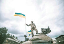 Trump’s DEMANDING Quid Pro Quo With UKRAINE Soldier on tank holding Ukrainian flag.
