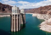 50-Year Pipe CATASTROPHE Drains Entire City A large dam structure with two towers over a blue water reservoir surrounded by rocky mountains