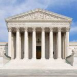 Front view of the Supreme Court building with large columns and steps under a blue sky