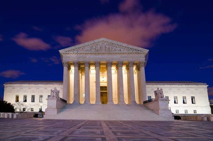 The Supreme Court building illuminated at night with a clear sky