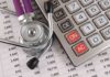 A stethoscope resting on a calculator and financial data sheets