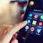 Finger tapping smartphone social media app icons.
