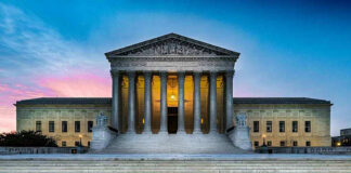 Supreme Court building with illuminated pillars and steps.