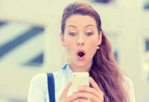 Surprised woman looking at her smartphone outdoors