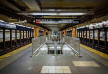 Subway station platform with directional signs overhead.