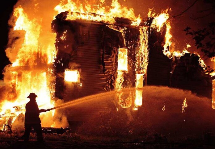 A firefighter battling a large house fire at night