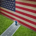 America’s Resurrection—Nobody Expected This! A man in a suit standing in front of a large American flag painted on a wall
