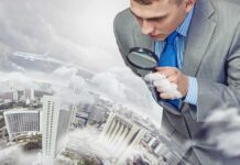 Businessman examining a cityscape with a magnifying glass amidst clouds and an airplane