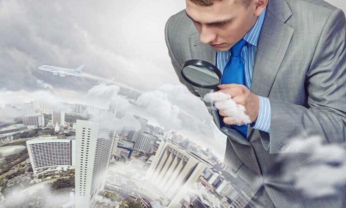 Businessman examining a cityscape with a magnifying glass amidst clouds and an airplane