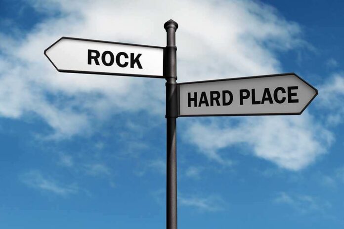 Directional signpost with ROCK and HARD PLACE labels against a blue sky