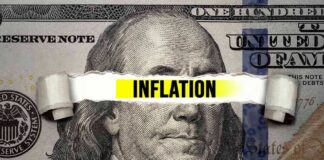 A torn paper strip with the word 'INFLATION' over a hundred dollar bill featuring Benjamin Franklin